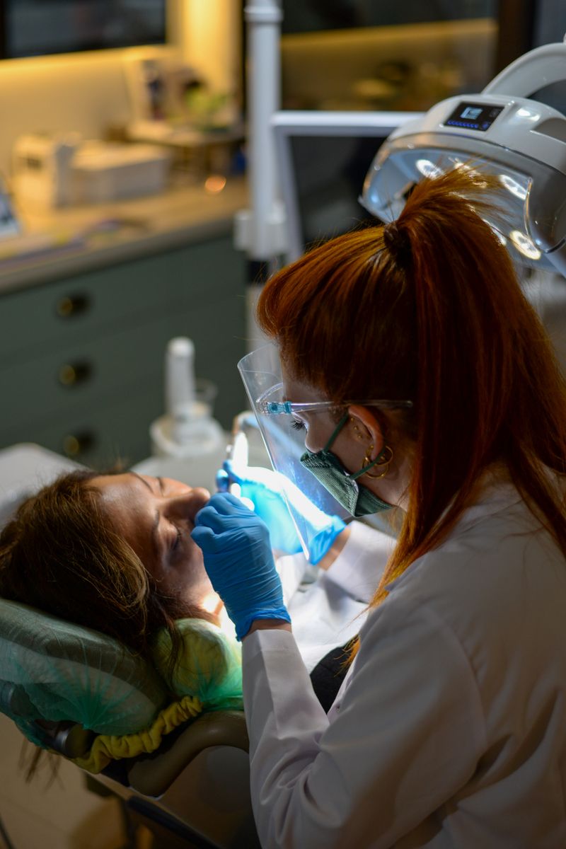 A dentist treating a smiling patient at Sharma Dental Care